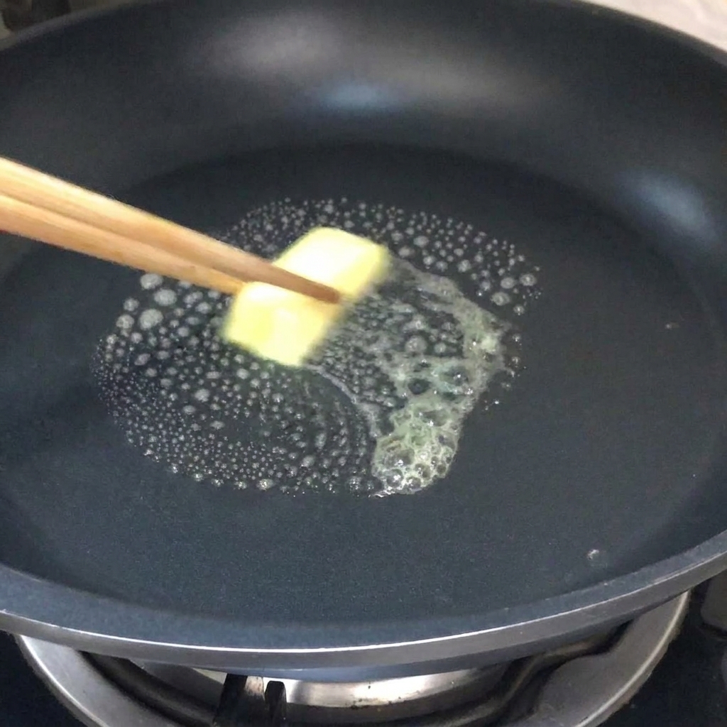 Une noix de beurre fondant dans une poêle chaude.
