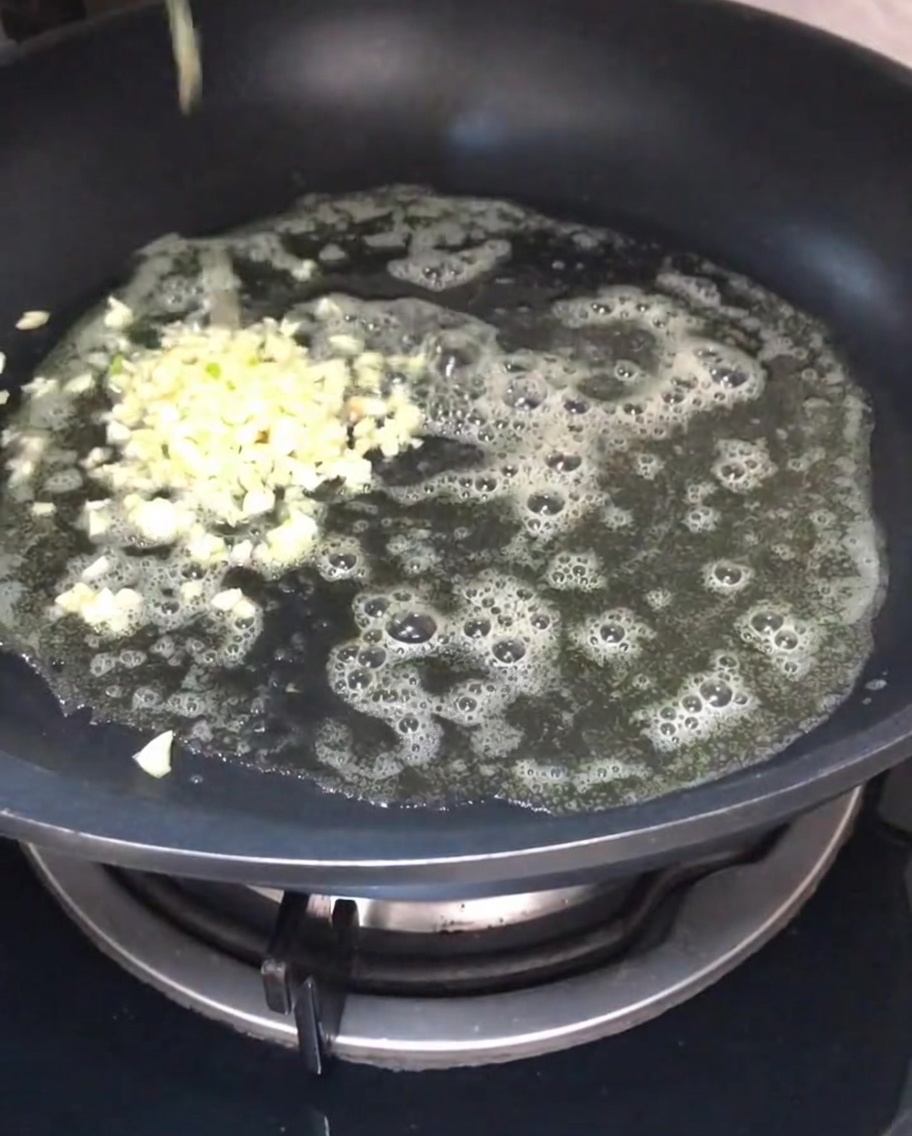 Ail haché revenant dans du beurre fondu dans une poêle.