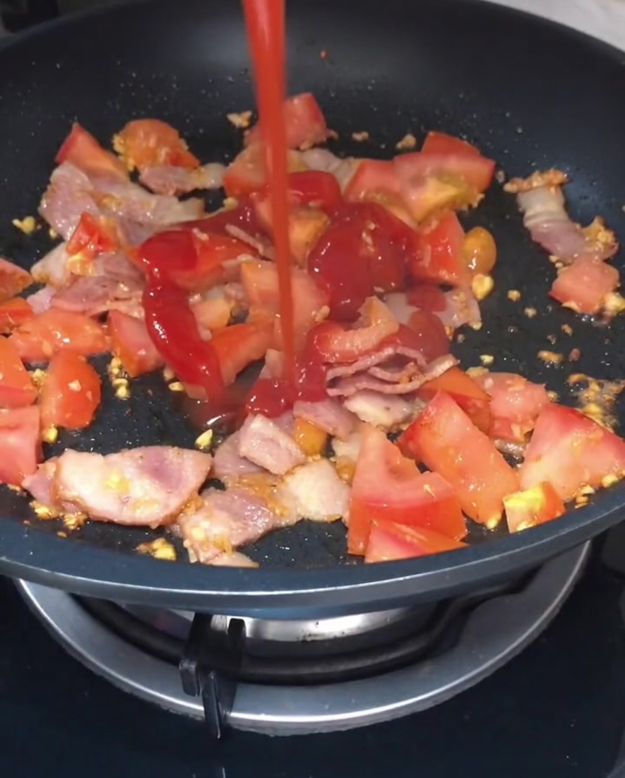 Ketchup et sauce soja légère versés sur le mélange de tomate et bacon.