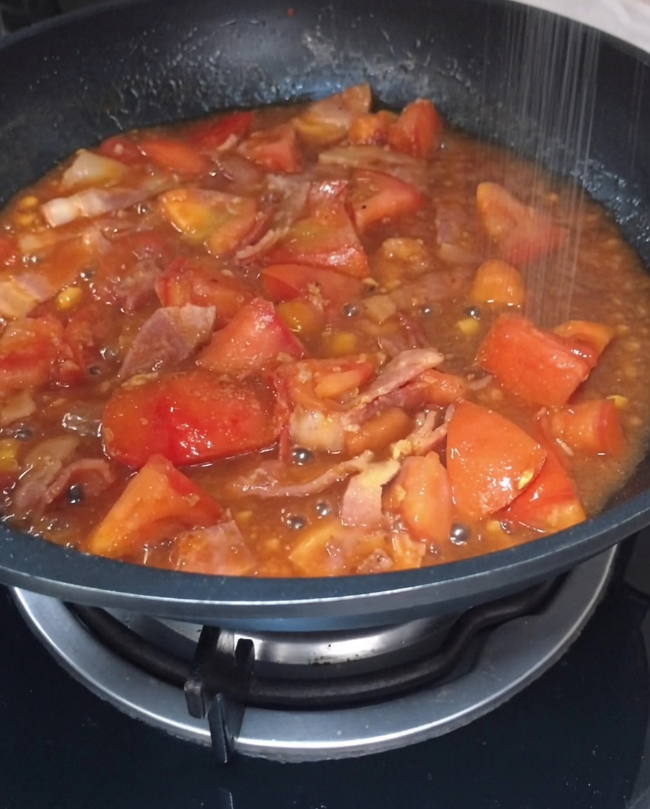 Sel et sucre saupoudrés dans la sauce tomate et bacon bouillonnante.