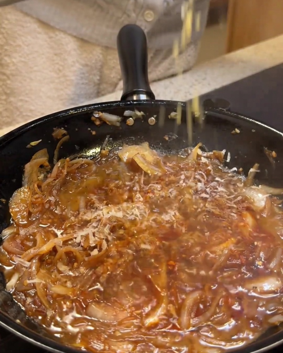 Ajout de parmesan râpé dans la sauce à la crème.