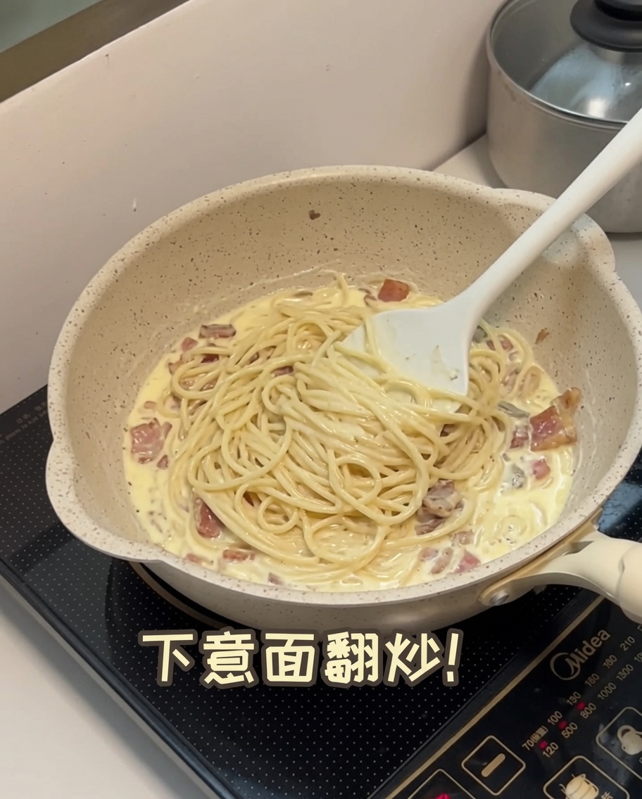 Spaghettis cuits mélangés dans une sauce crémeuse aux champignons dans une poêle.