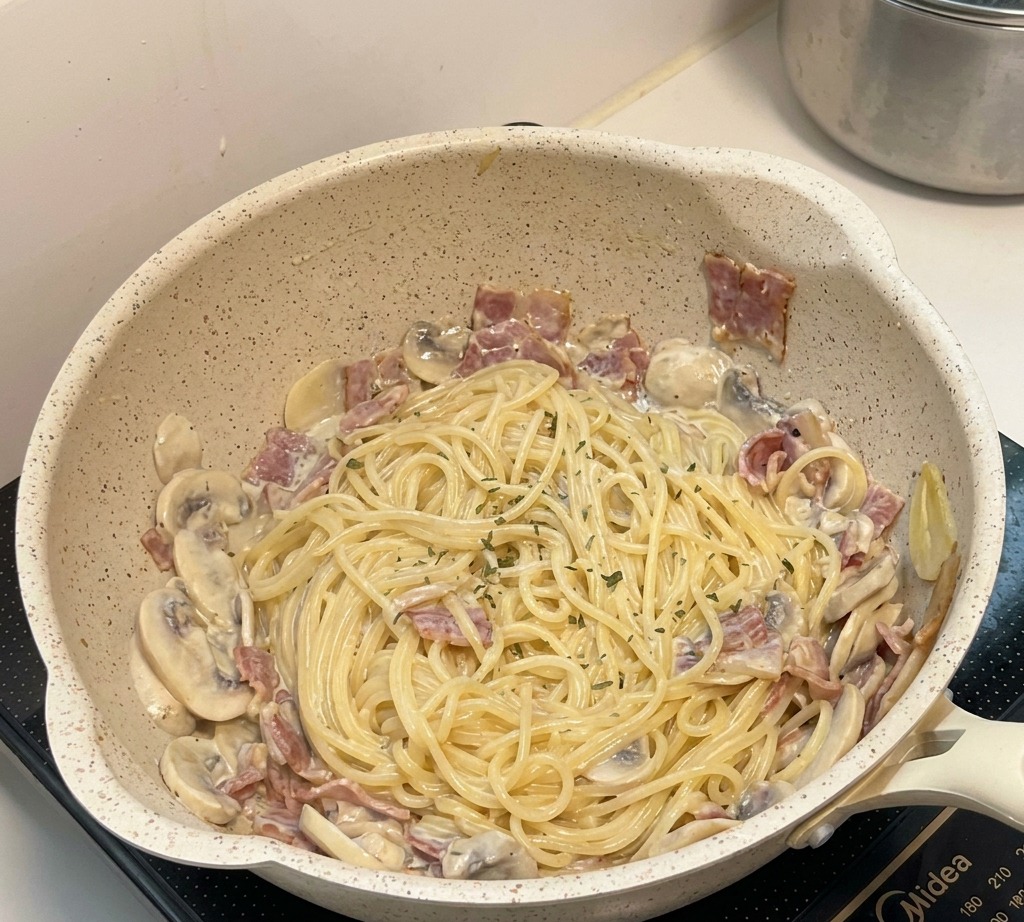 Le plat final de pâtes crémeuses aux champignons dans la poêle, garni dherbes et prêt à être servi.
