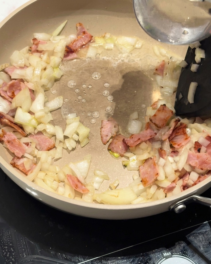 Nouilles torsadées placées dans la poêle sur la base de bacon et doignon.
