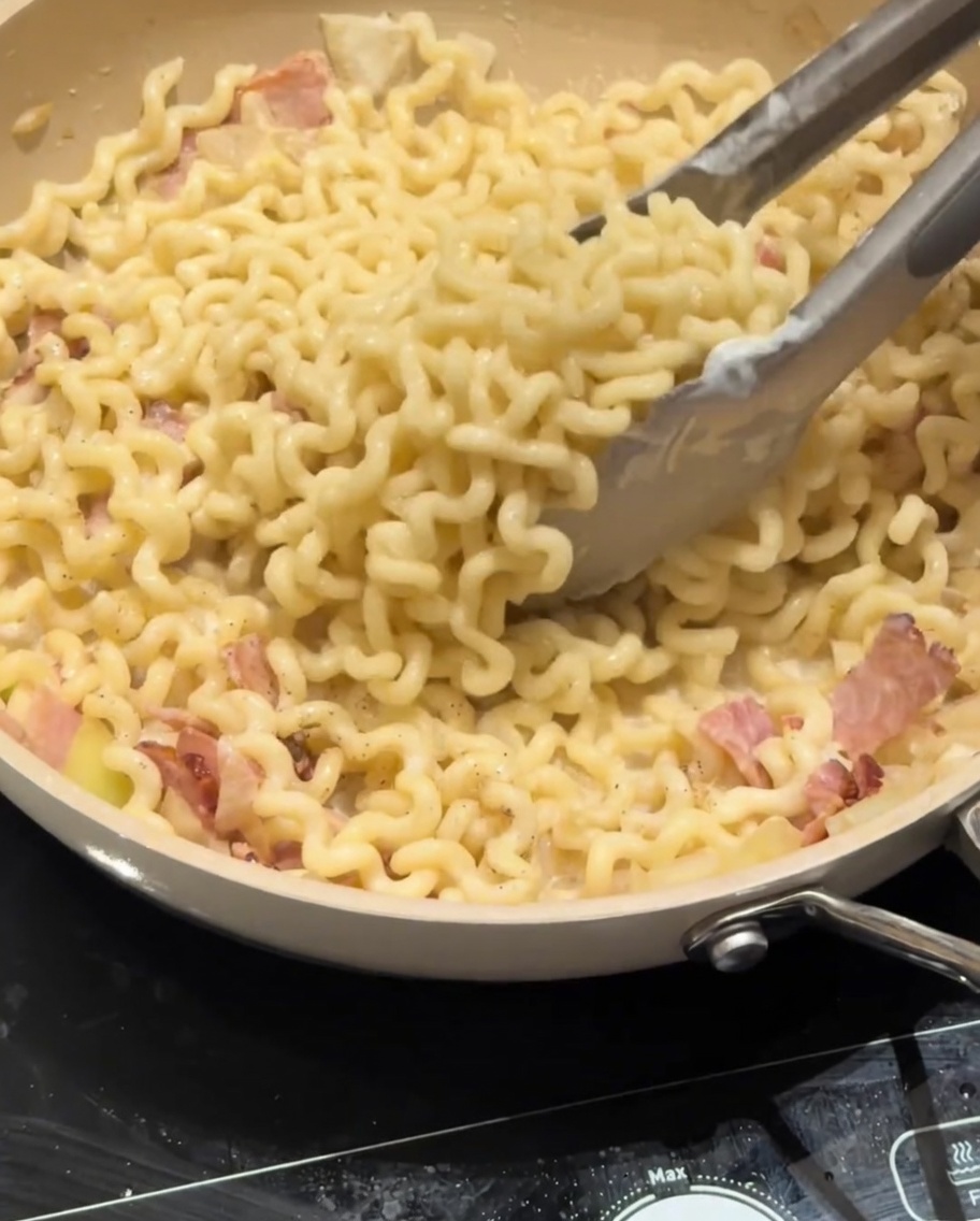 Du parmesan râpé saupoudré sur les pâtes crémeuses.