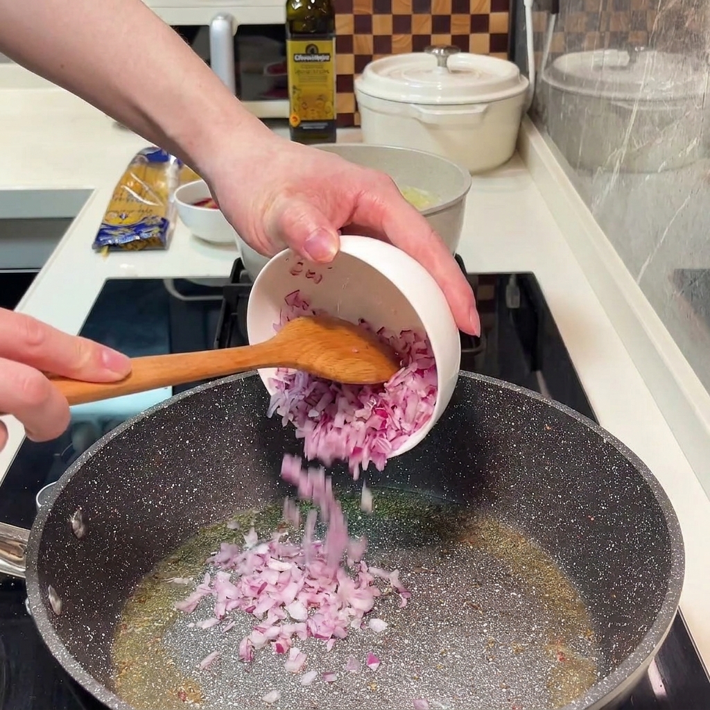 De loignon rouge haché qui rissole dans une poêle avec de lhuile dolive.