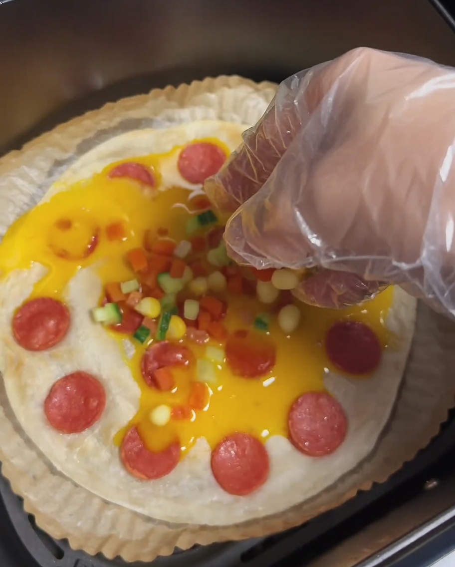 Une crêpe à la ciboule avec des œufs, des saucisses et des petits morceaux colorés de carottes, concombres et grains de maïs.