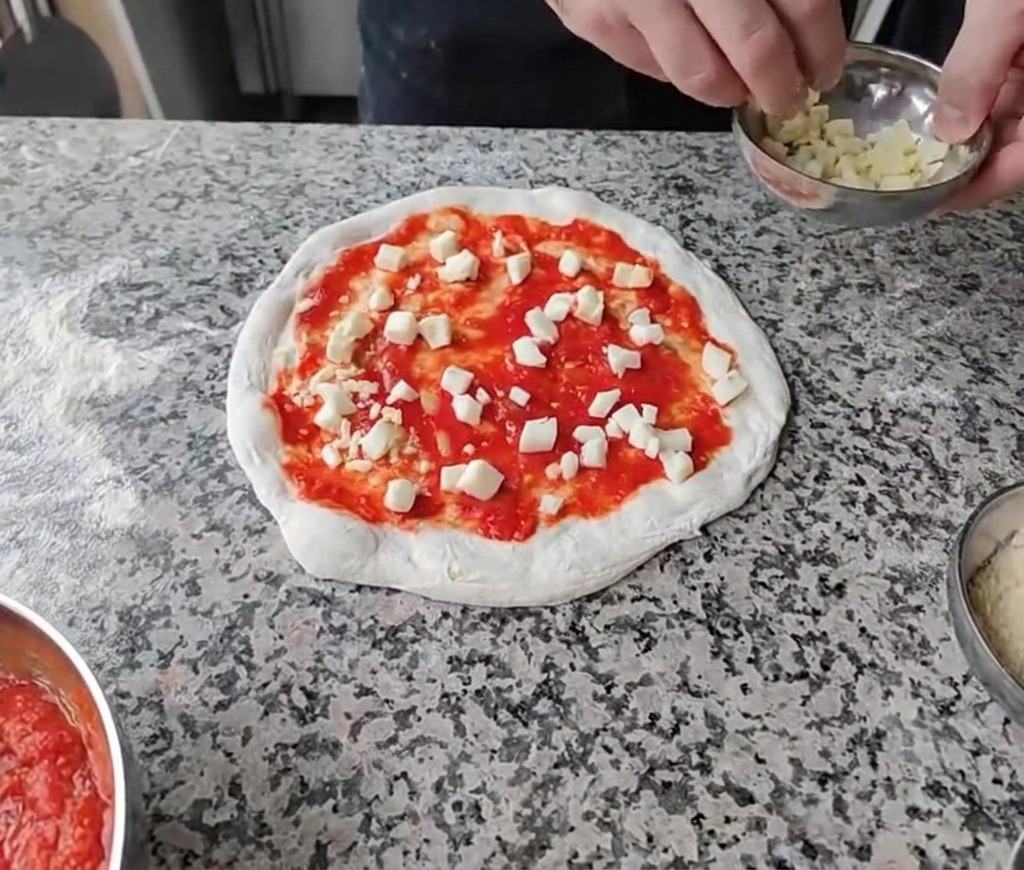 Saupoudrage de dés de fromages blancs sur la base de sauce tomate.