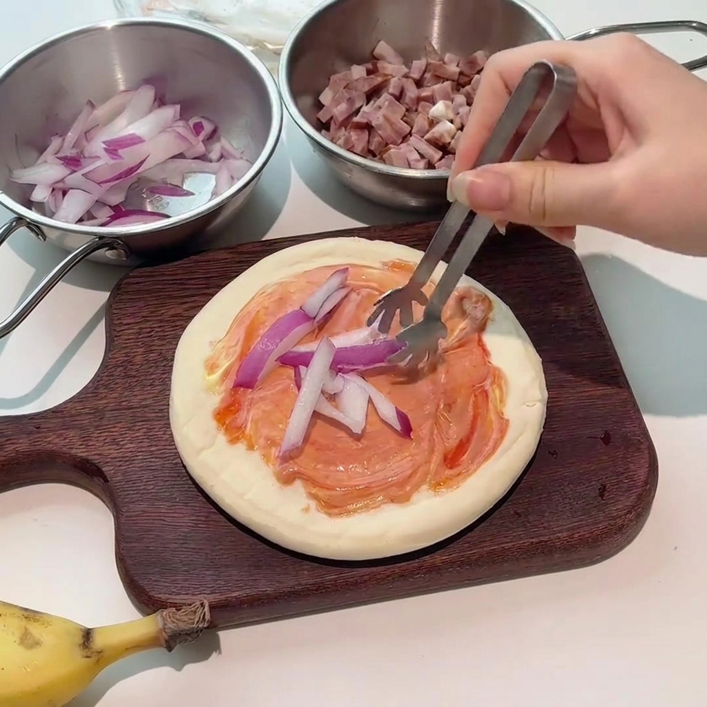 Pinces déposant des lamelles doignon rouge frais sur la pizza garnie de sauce.