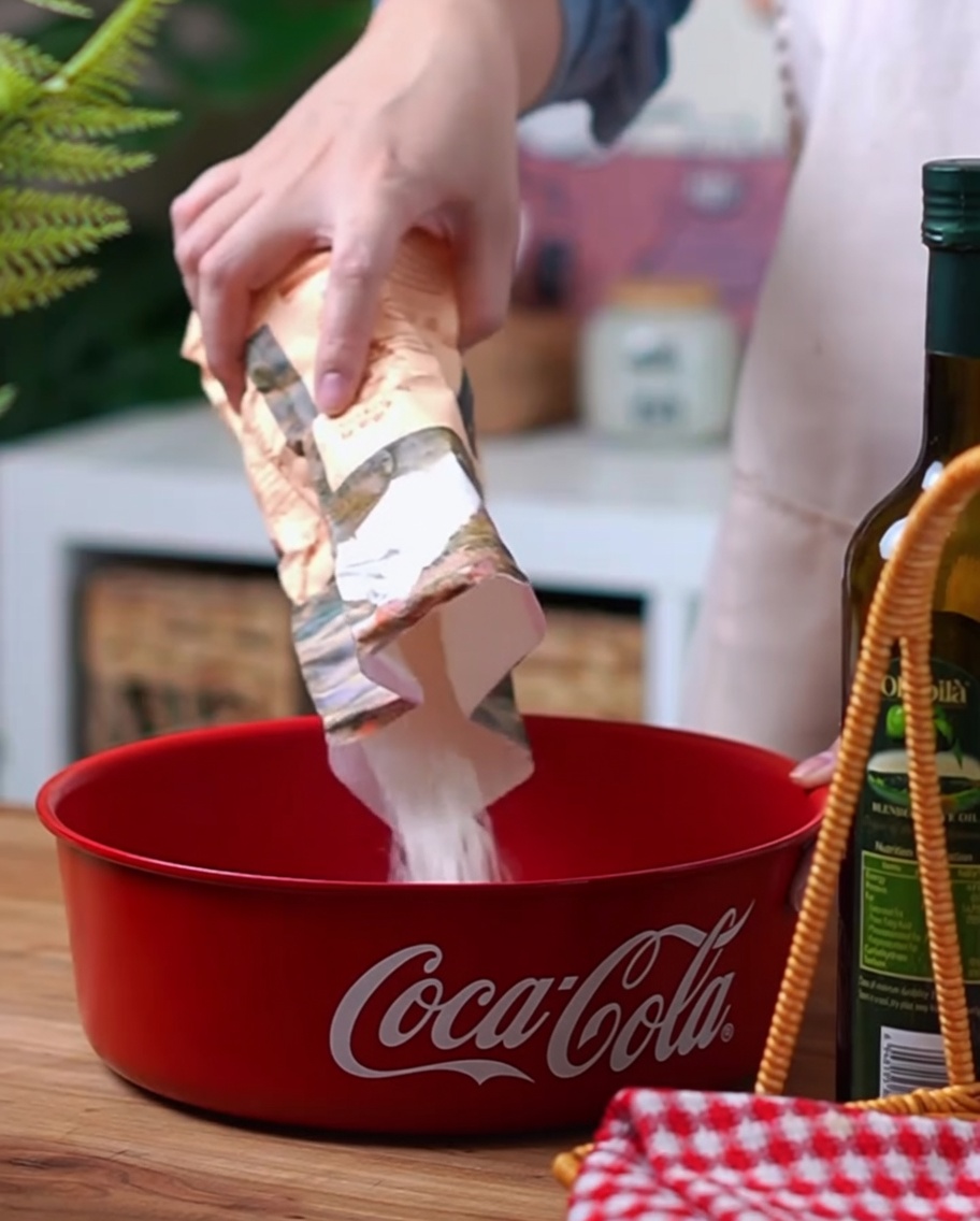 Gros plan sur la farine riche en gluten, la levure et le sel versés dans un bol rouge Coca-Cola.