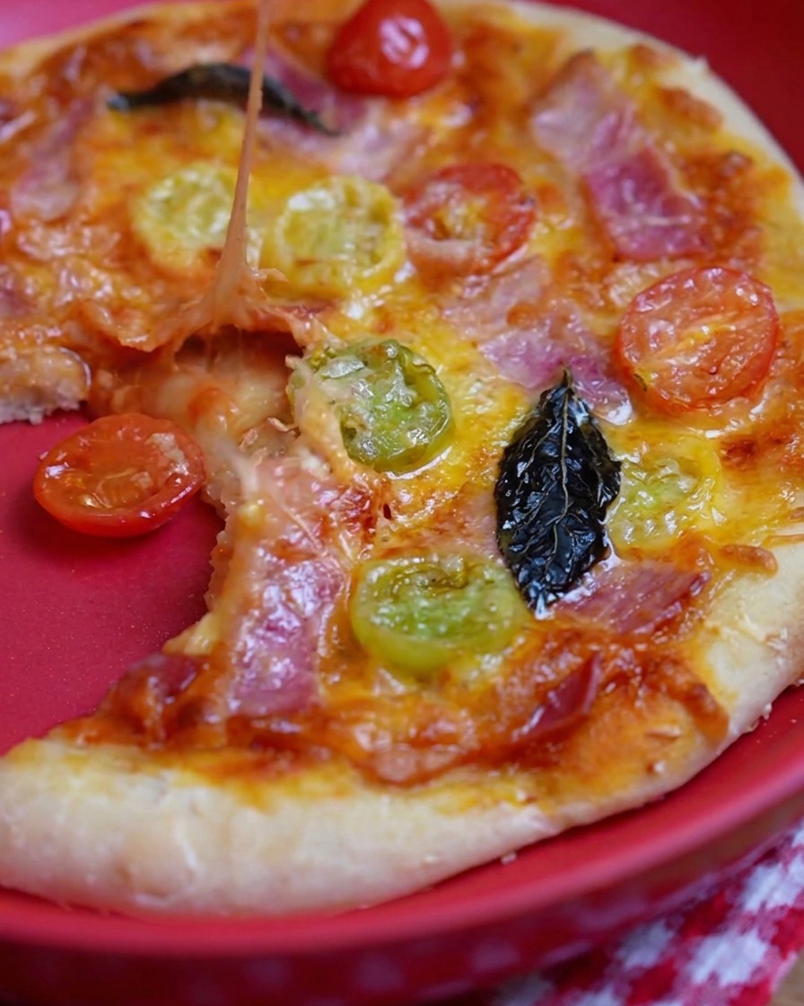 Une cuillère en métal étalant une sauce tomate rouge sur une base de pâte à pizza crue.