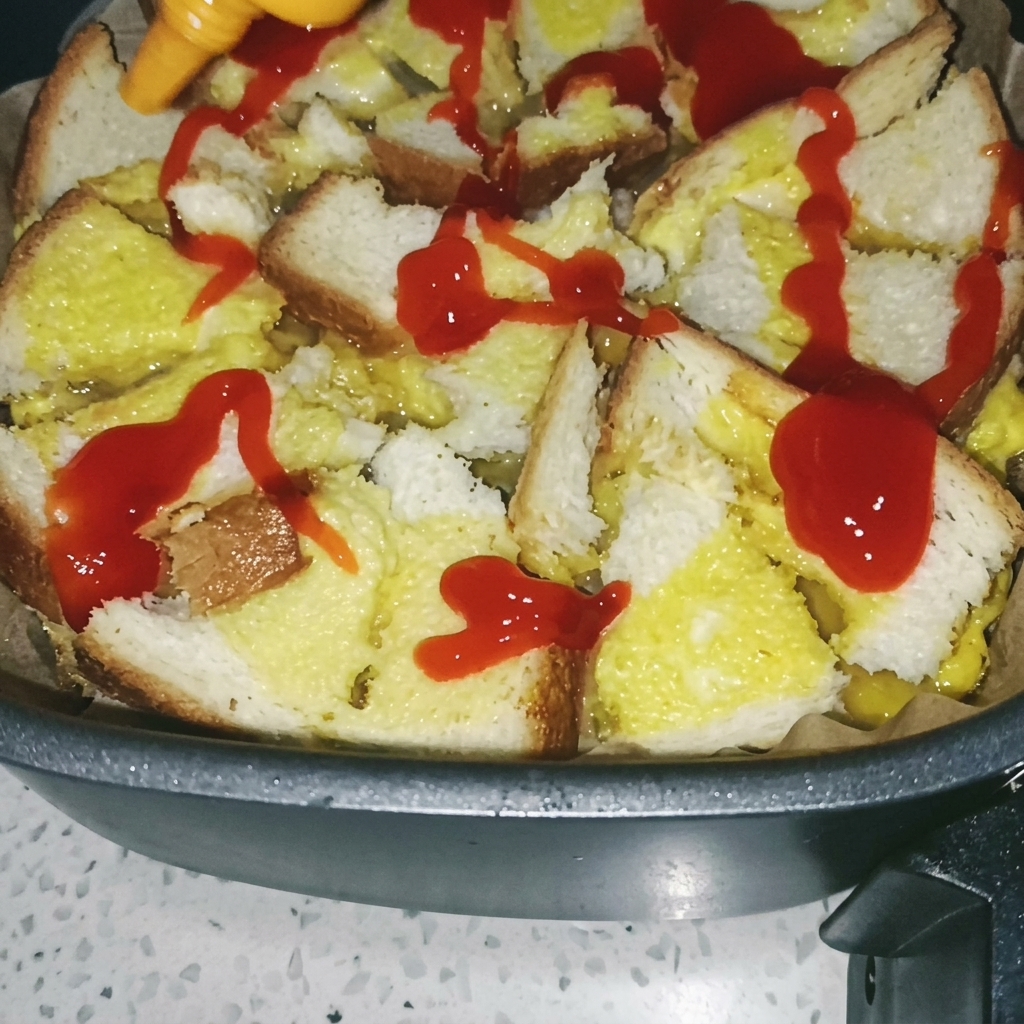 Un pinceau étalant de la sauce tomate rouge sur la base pain-œuf cuite dans lAir Fryer.