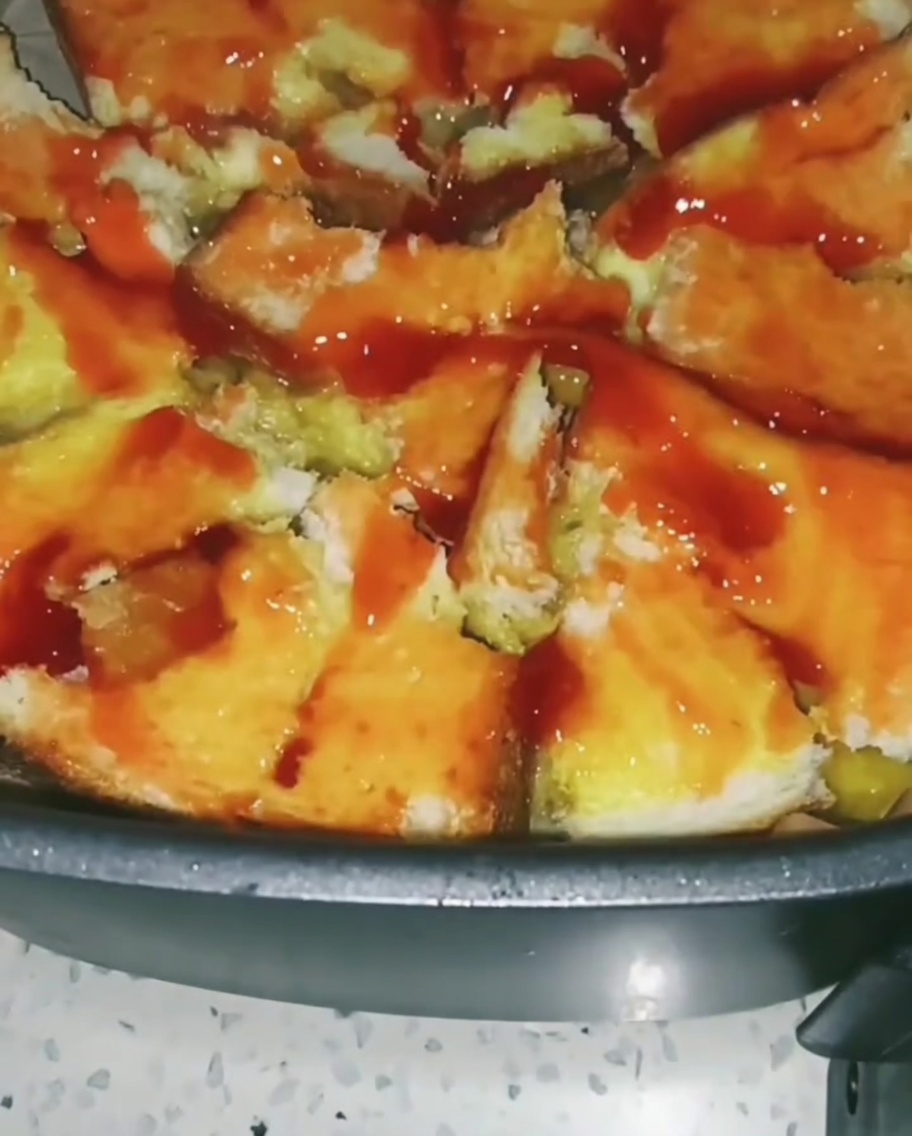 Un mélange coloré de légumes comme du maïs et des petits pois saupoudré sur la base de pain recouverte de sauce tomate.