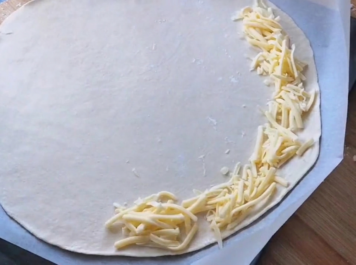 La sauce blanche est étalée sur une base de pâte à pizza ronde.