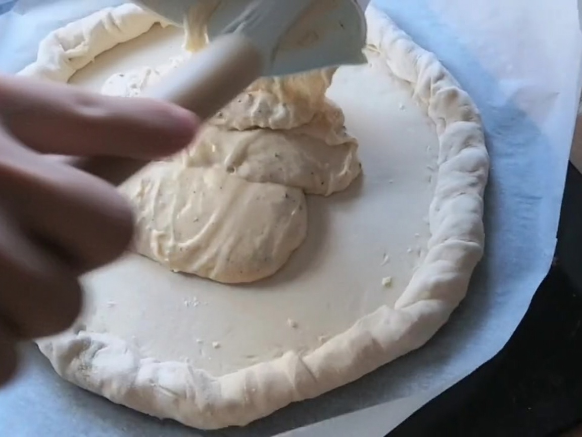 Tranches de pepperoni et de salami disposées sur une pâte à pizza couverte de sauce.