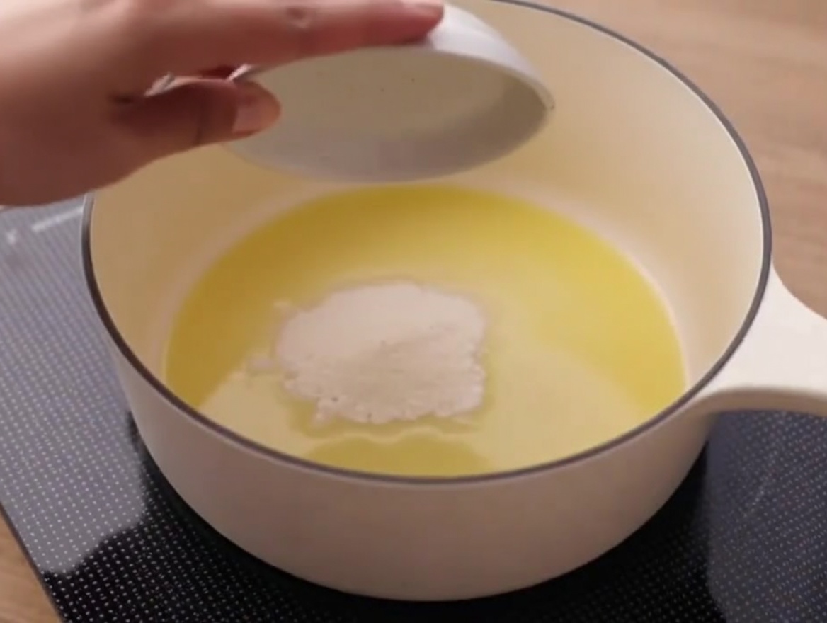 De la farine mélangée à du beurre fondu dans une casserole, formant une pâte.
