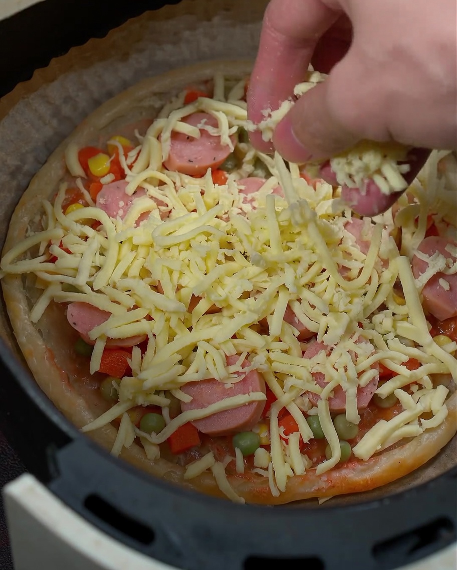 Gros plan de la mozzarella râpée saupoudrée sur les ingrédients de la pizza.