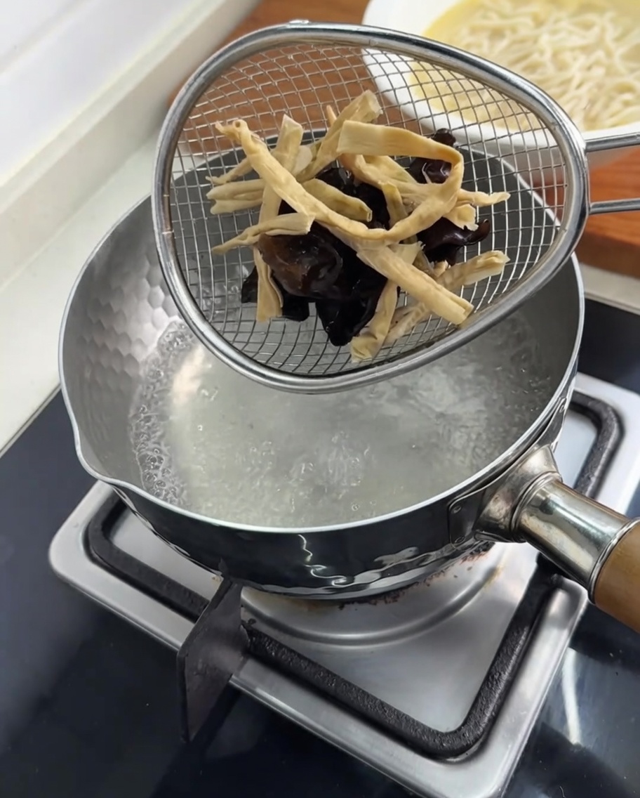Champignons et pousses de bambou blanchis dans une passoire.