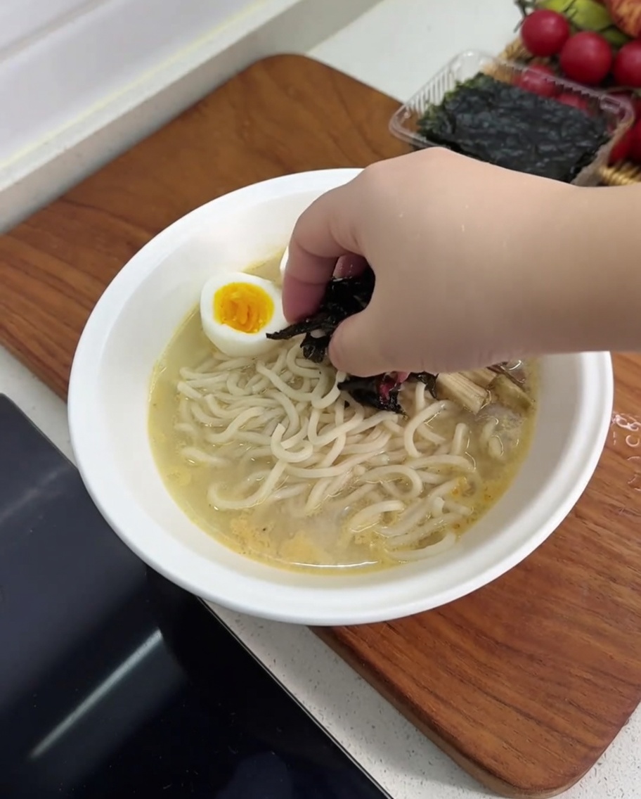 Bol de ramen garni dœuf dur, champignons, pousses de bambou et nori.