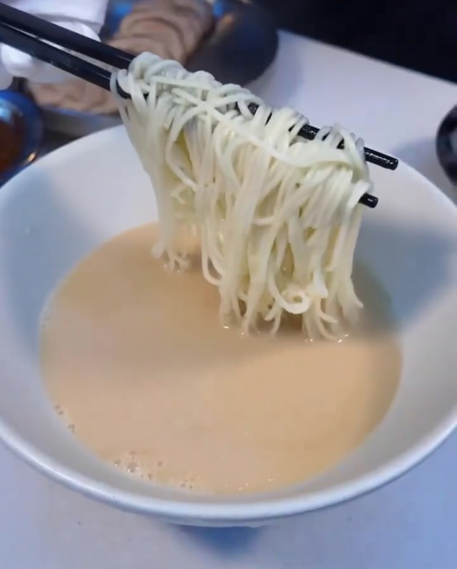 Nouilles ramen fumantes déposées dans le bol de bouillon.