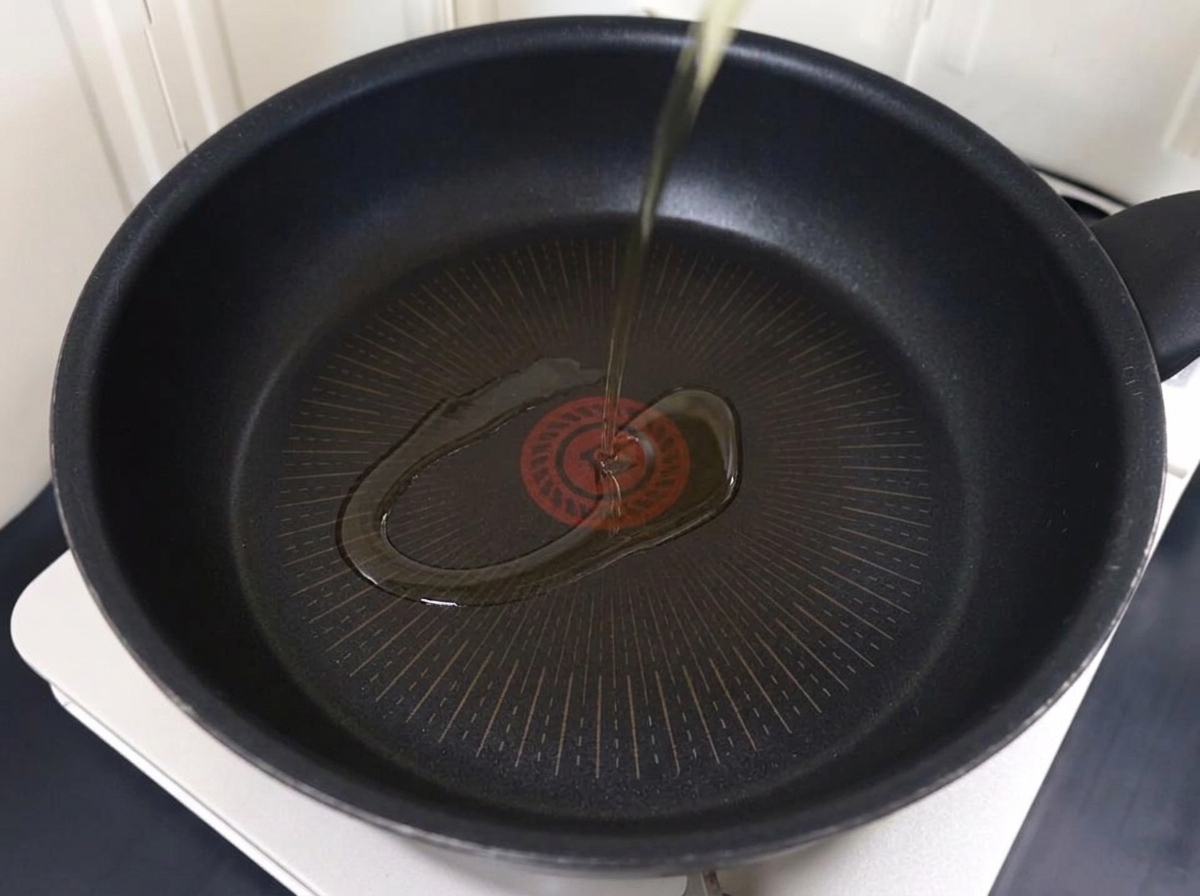 Porc finement tranché doré dans une poêle avec de lhuile chaude.
