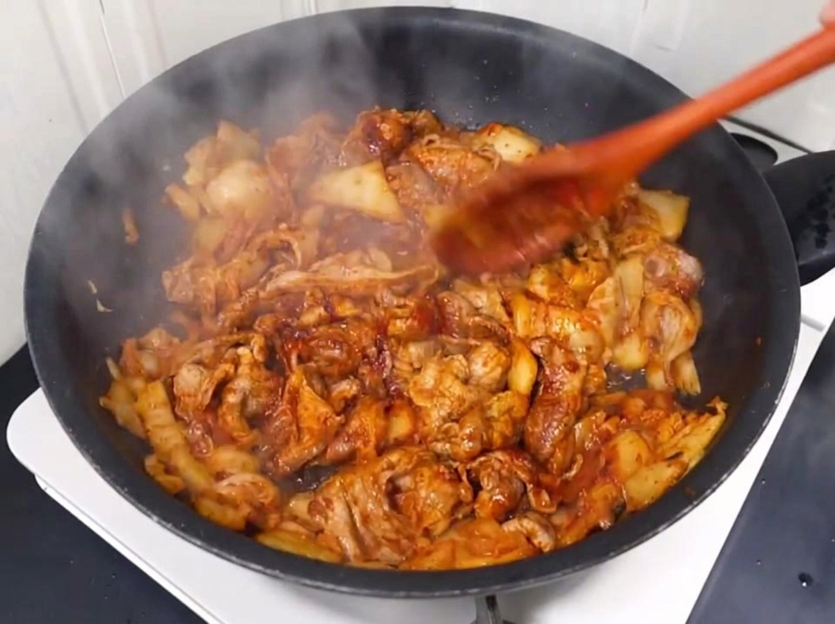 Eau versée dans la poêle avec le mélange de porc et kimchi sauté.