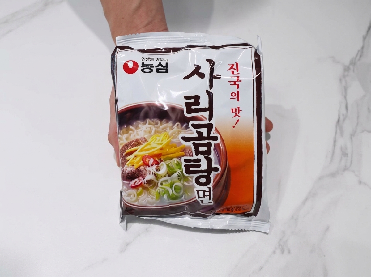 Bloc de nouilles ramen ajouté dans le bouillon bouillant de porc et kimchi.