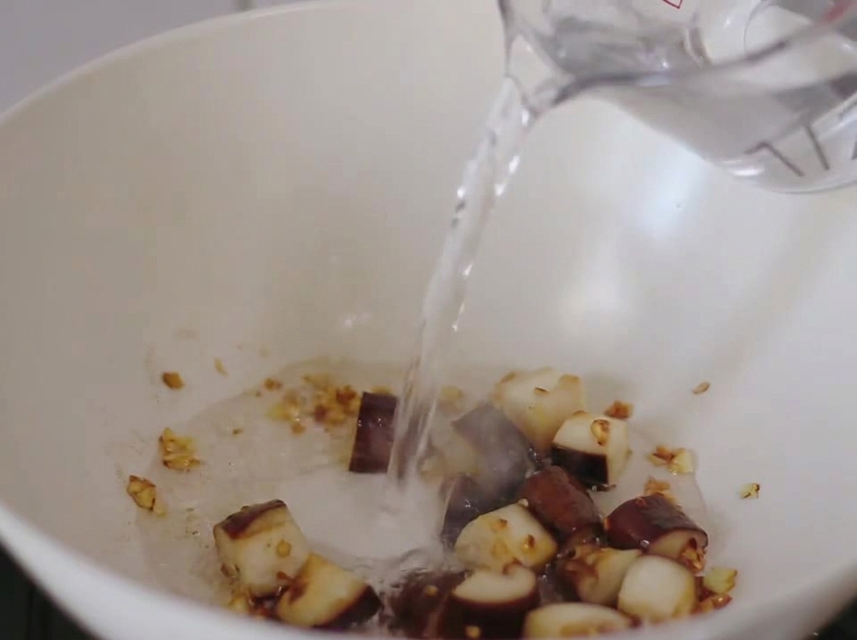 Eau versée dans la poêle contenant les champignons et lail sautés.