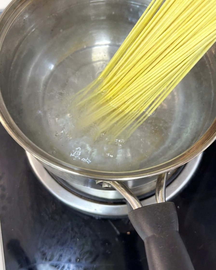 Nouilles dans une casserole deau bouillante remuées avec des baguettes.