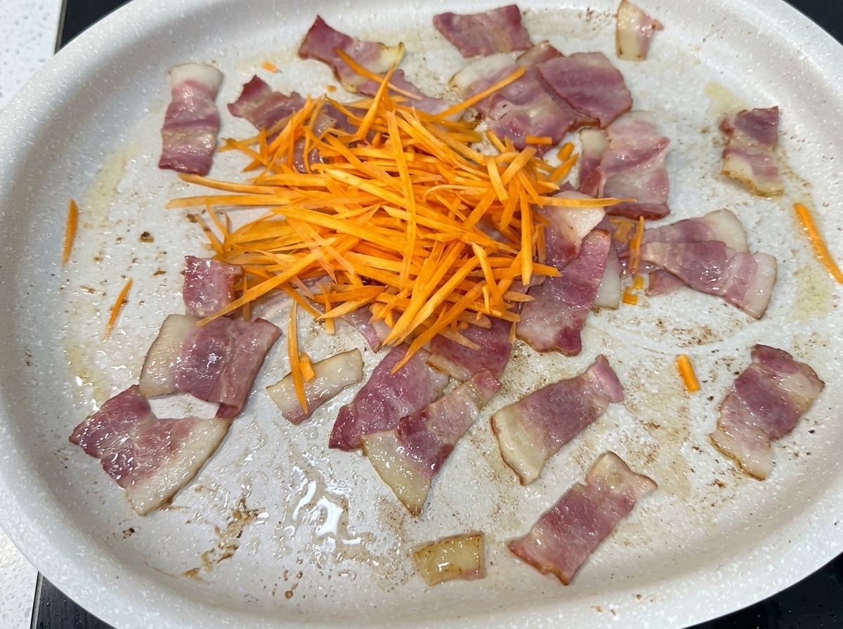 Mélange de carottes, oignons, chou et pousses de soja ajouté à la poêle avec le lard.