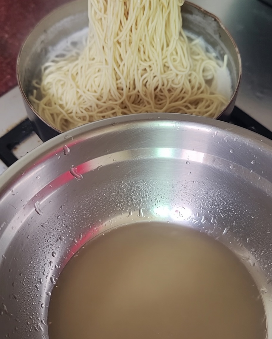 Nouilles cuites retirées dune casserole avec des baguettes.