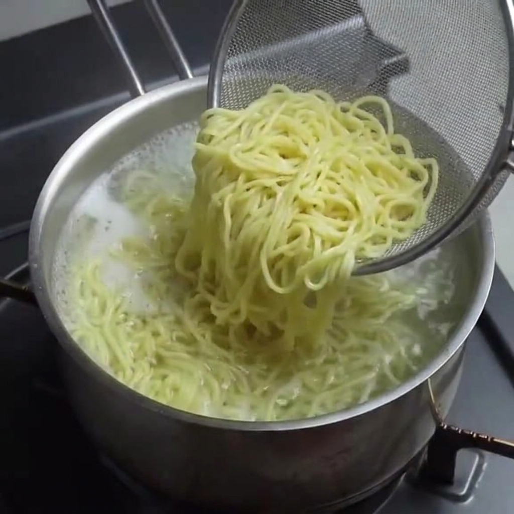 Nouilles ramen cuites retirées de la casserole avec une écumoire.