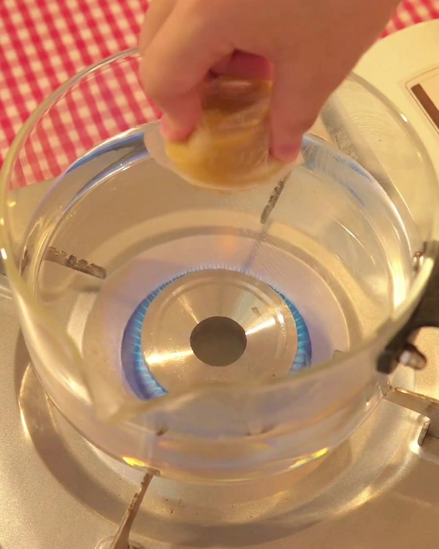 Une main déposant un cube de bouillon de volaille dans une casserole deau bouillante.