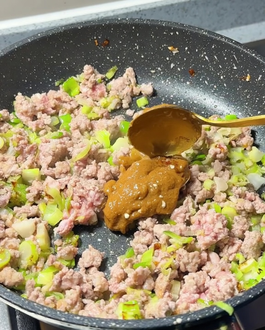 Une cuillère de pâte de miso ajoutée dans la poêle avec la viande.