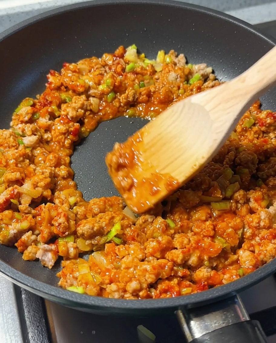 Cuillère en bois remuant la viande pendant lajout de sauce soja.