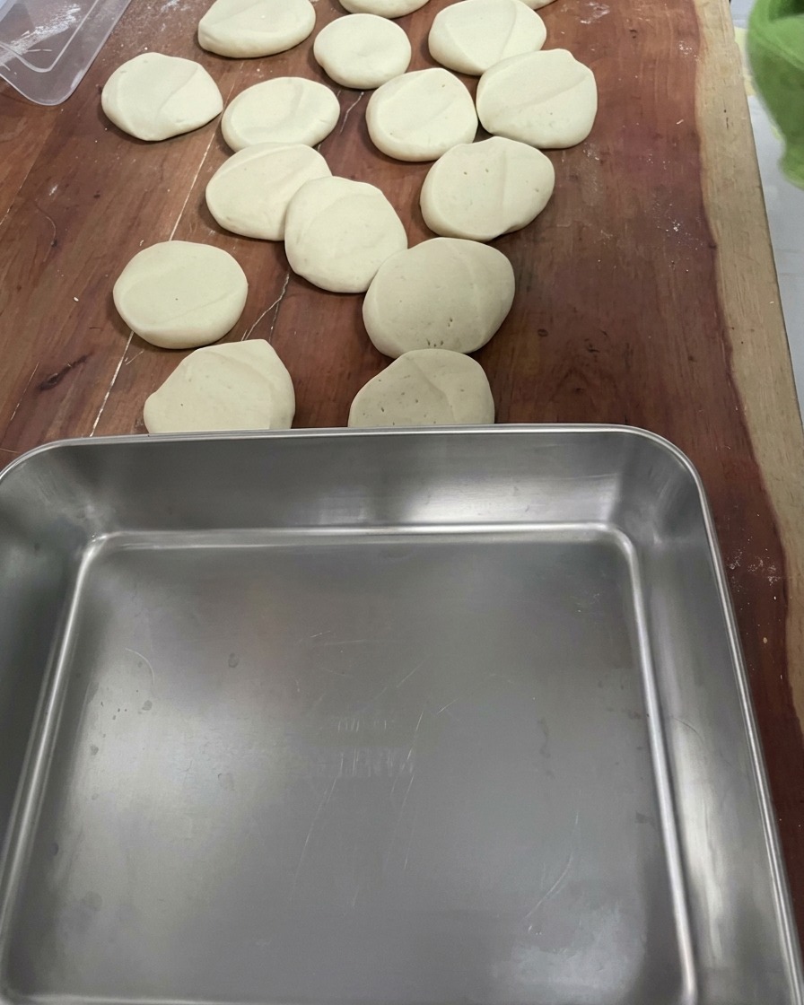 Plusieurs petits morceaux de pâte uniformes disposés sur une surface en bois.