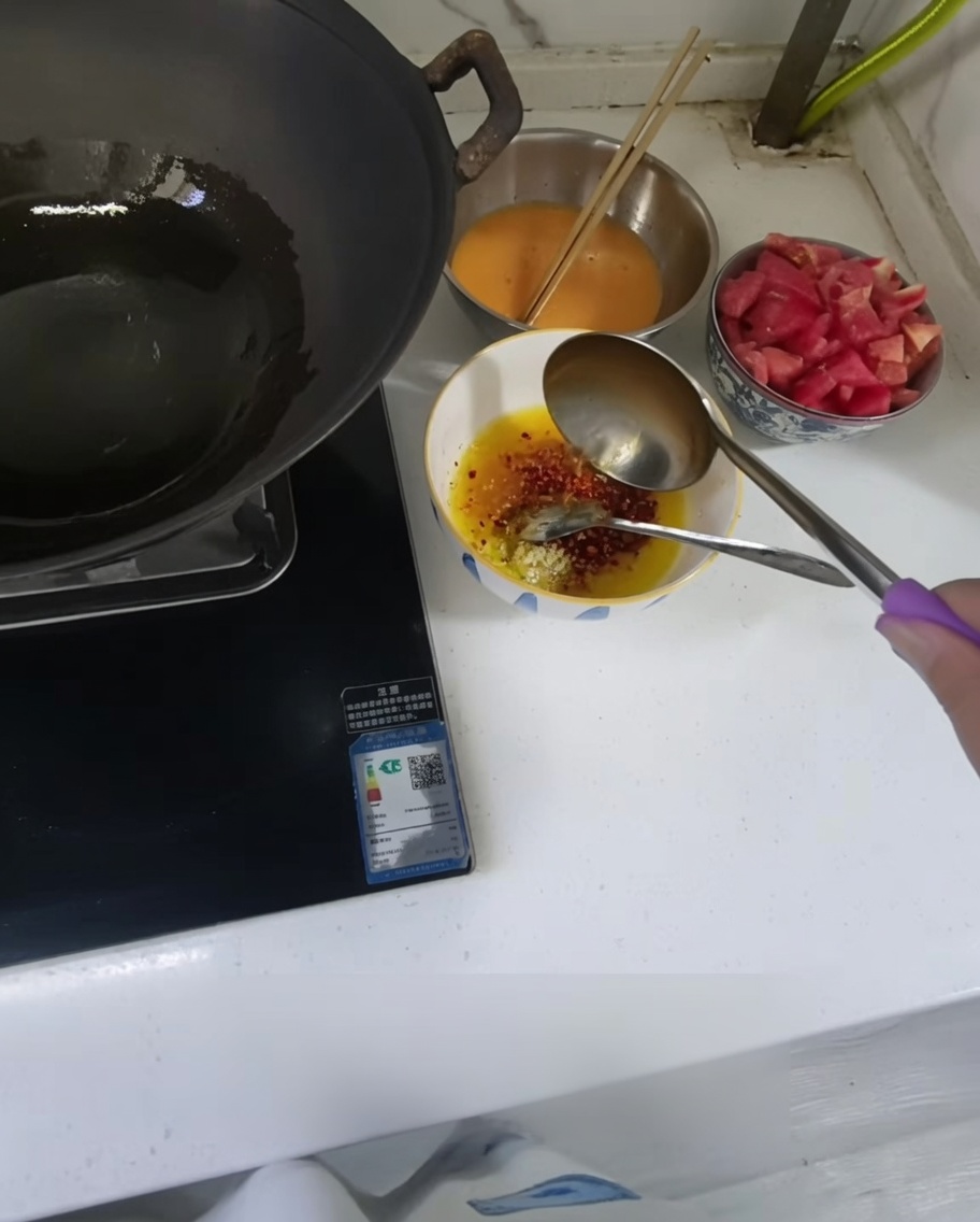 Huile chaude versée dans un petit bol contenant de lail haché et du piment en poudre.