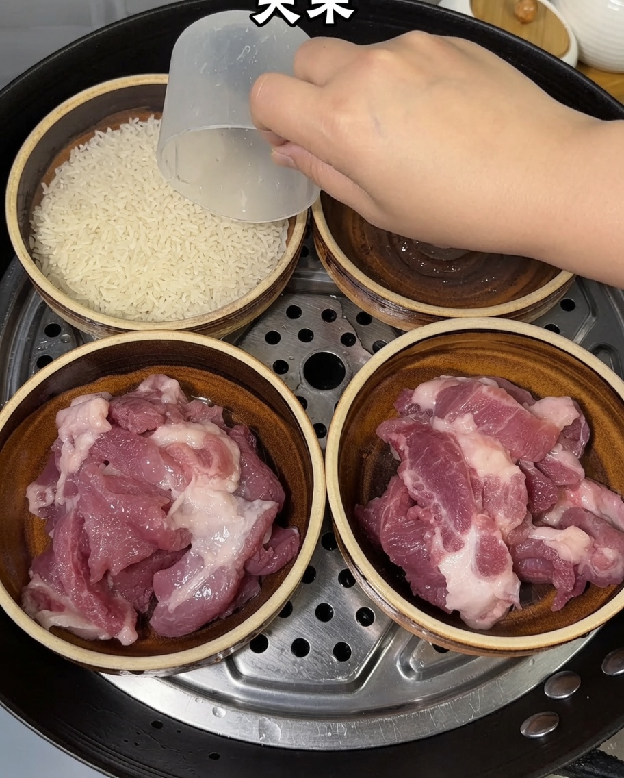 Une main utilisant un verre doseur pour ajouter du riz cru dans les bols contenant déjà le porc.