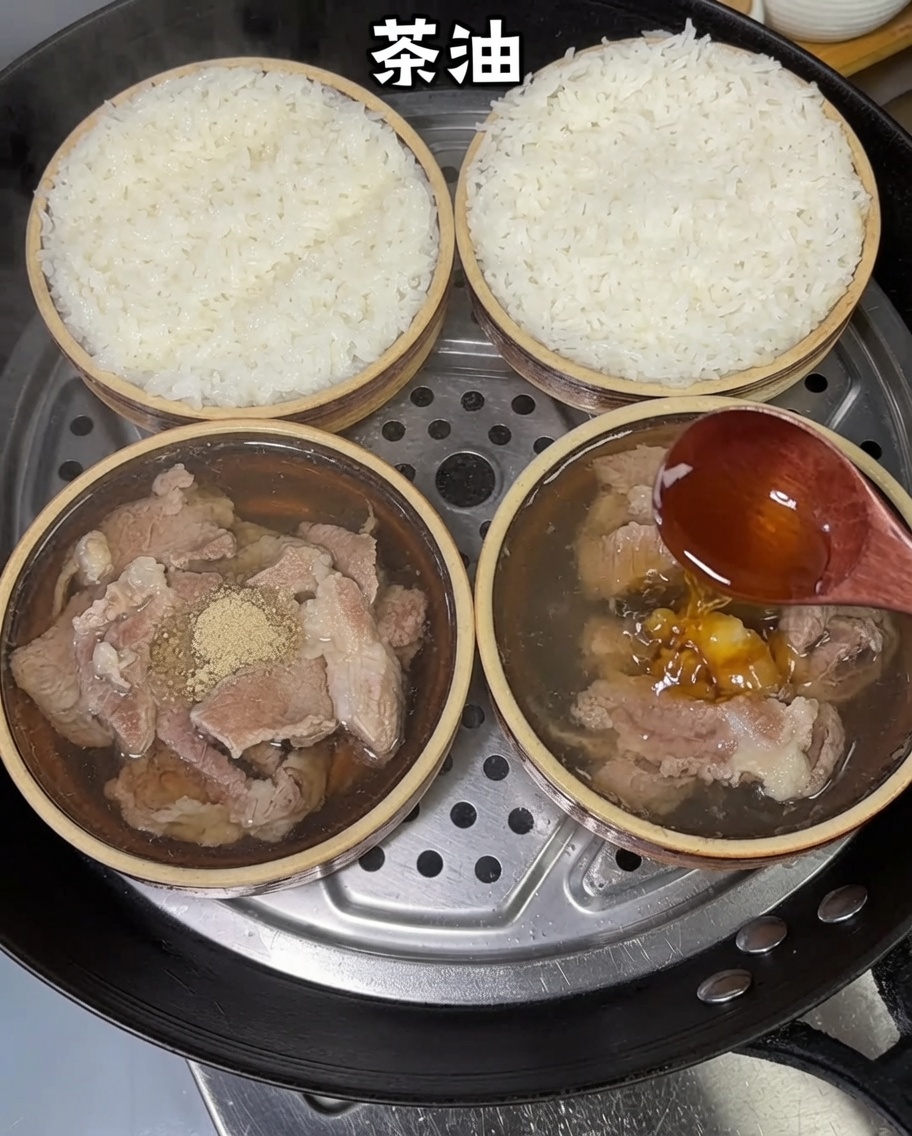 Huile de thé versée à partir dune cuillère en bois sur les bols de riz au porc vapeur.