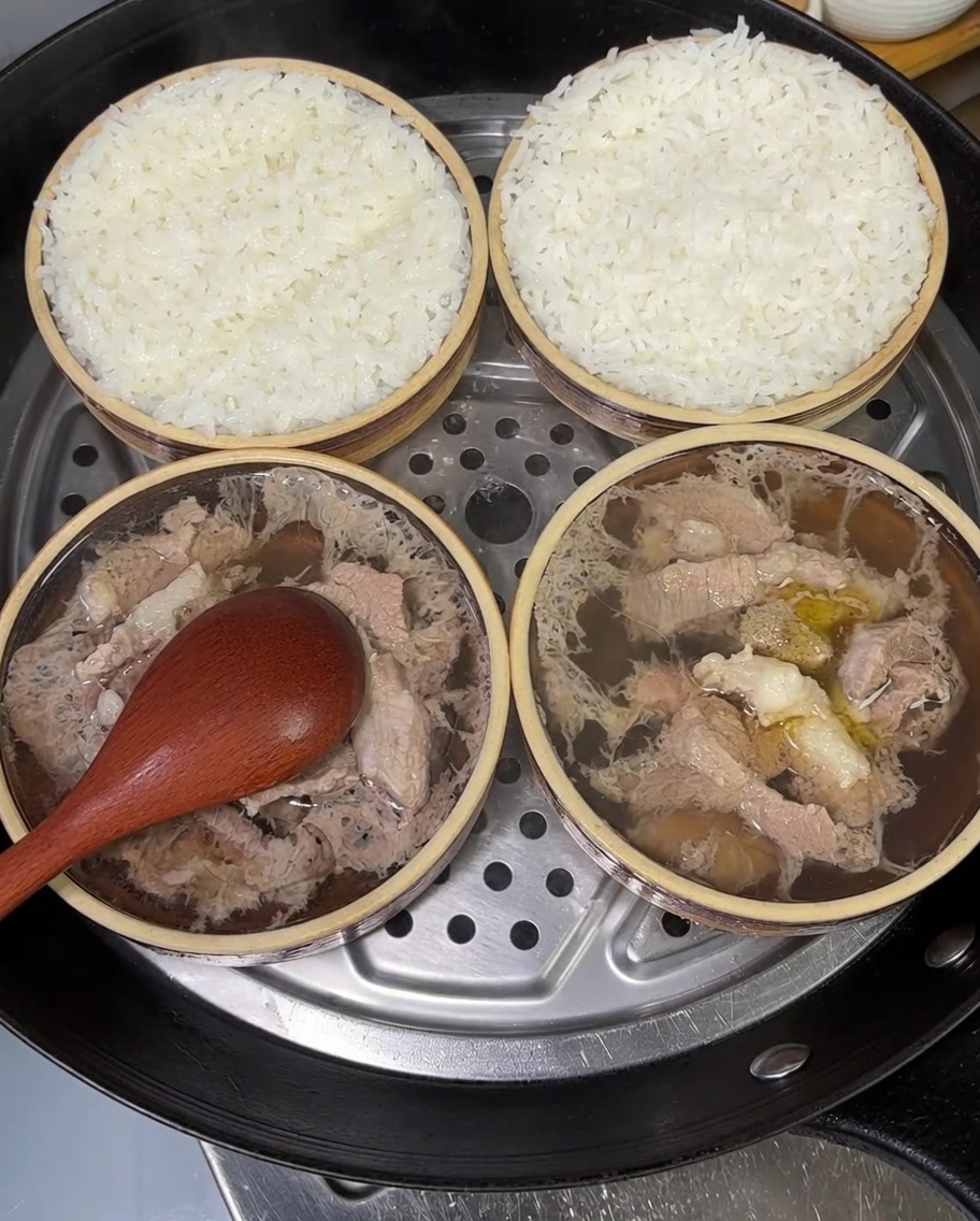 Deux petits bols de riz au porc vapeur garnis doignons verts frais hachés.