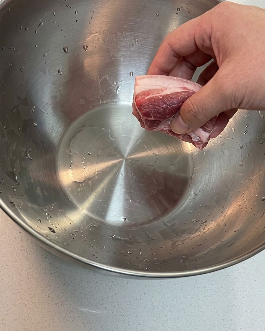 Poitrine et os de porc trempant dans un grand bol deau froide.