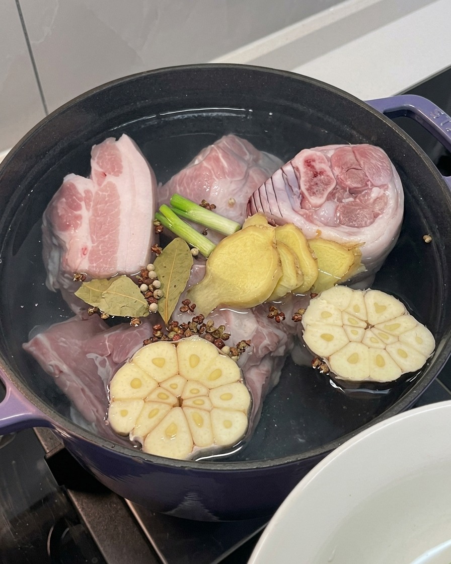 Viande de porc dans la marmite avec oignon, ail, gingembre, oignons verts et épices entières ajoutés.
