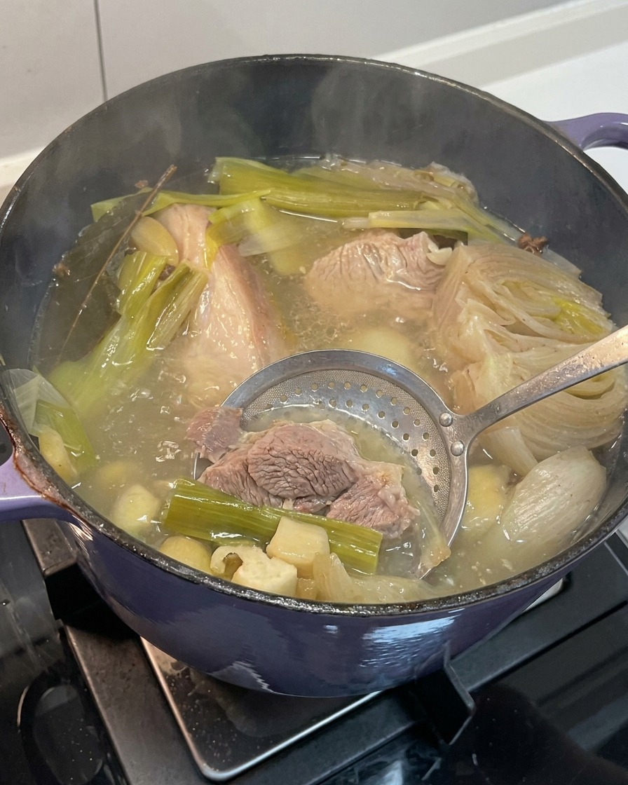 Retrait des morceaux doignon, dail et de gingembre ramollis du bouillon dos de porc fini.