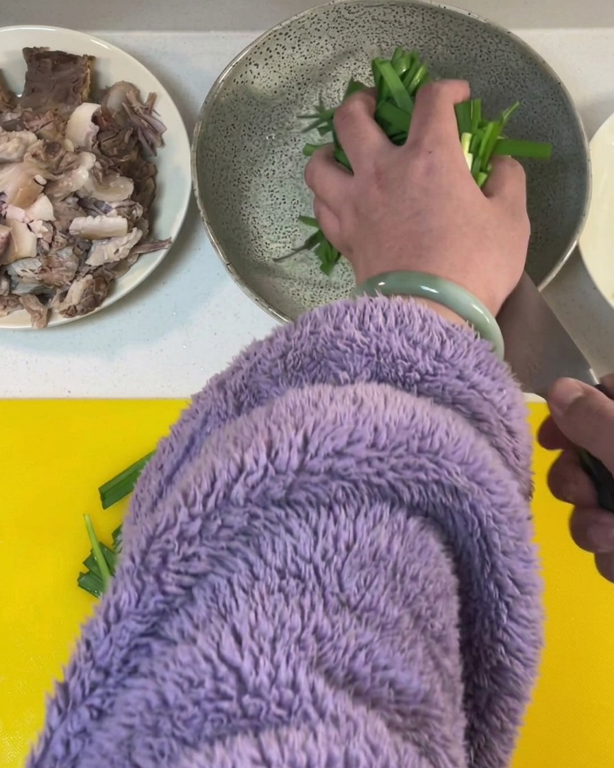 Ciboulette fraîche coupée en segments sur une planche à découper jaune vif.