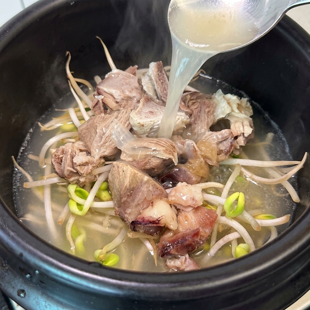 Une louche versant le bouillon dos chaud sur la viande et les pousses.