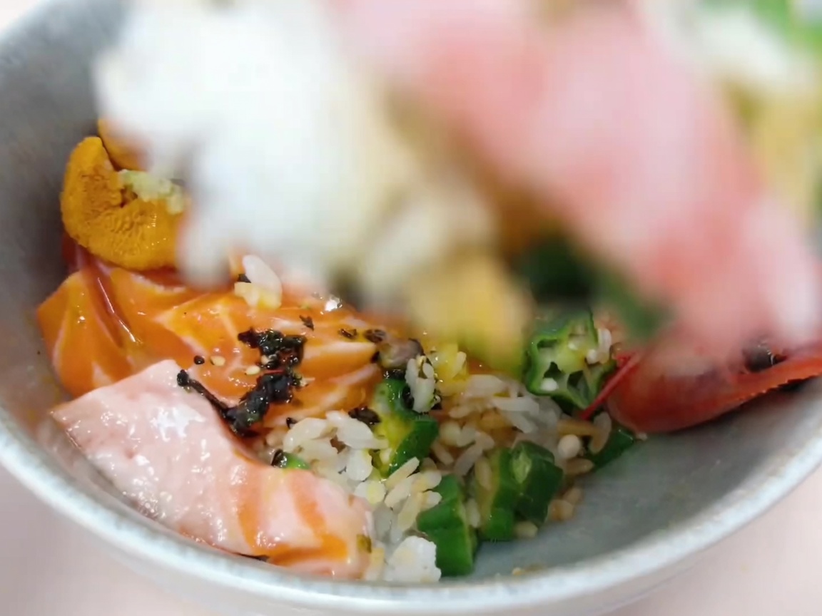 Ingrédients soigneusement disposés sur le riz pour créer la base du donburi.