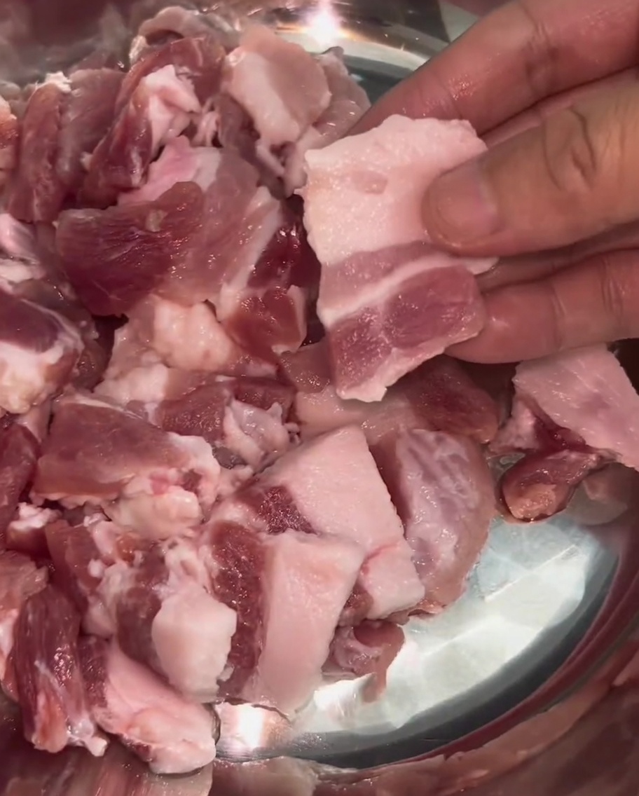 Tranches fines et uniformes de poitrine de porc avec des couches de gras et de maigre visibles dans un bol.