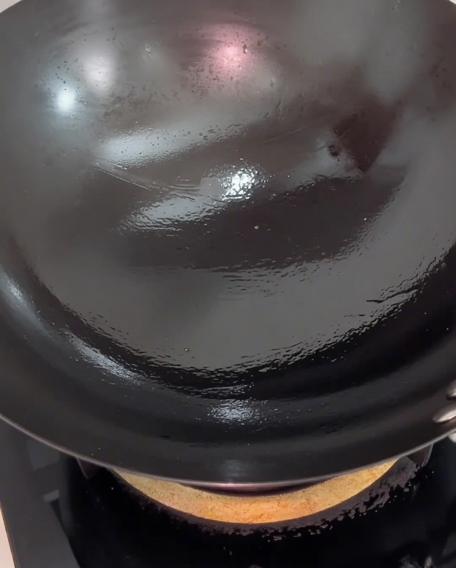 Tranches de porc sautant dans le wok, présentant un léger marquage doré.