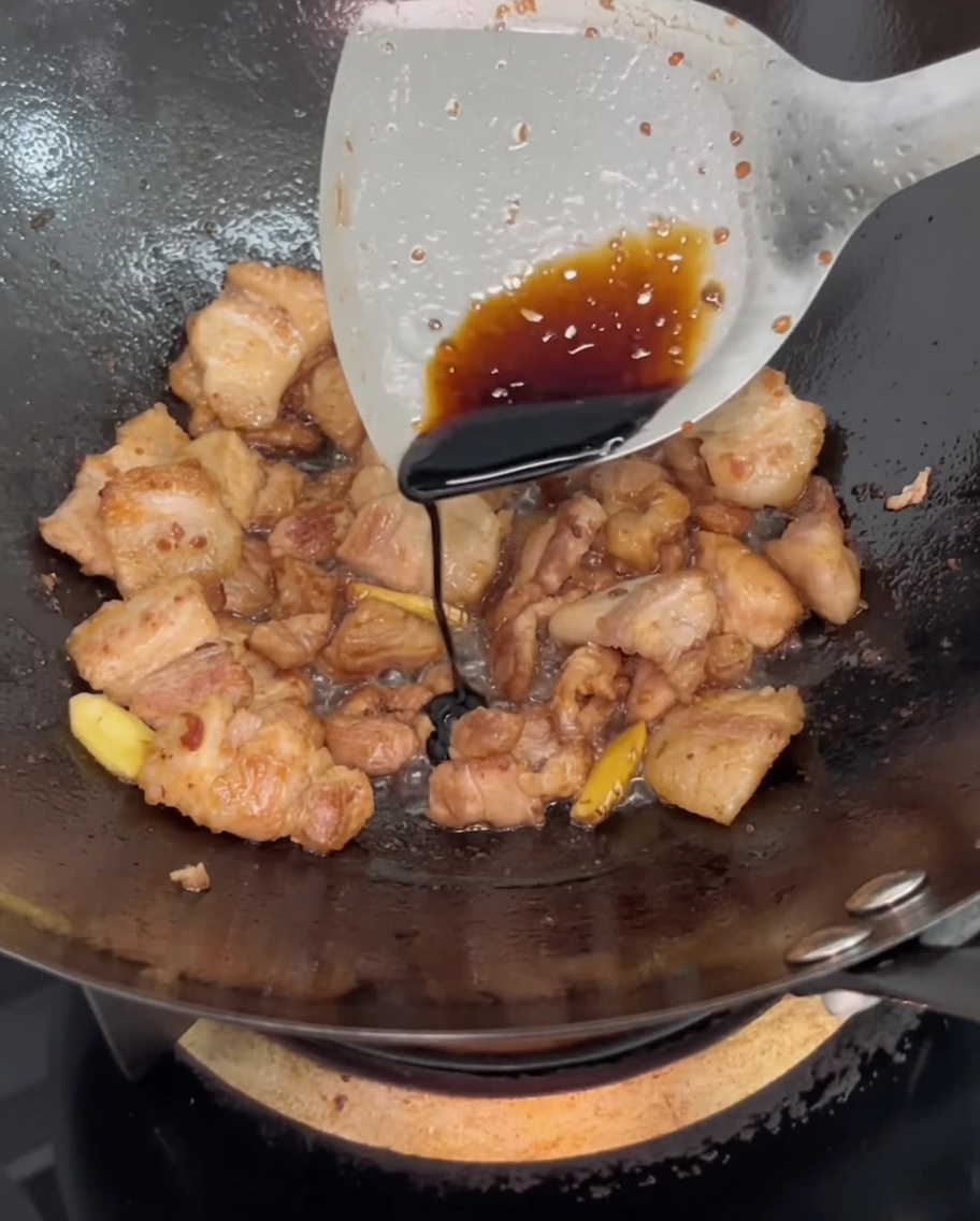 Sauce soja foncée versée à la spatule sur le porc.