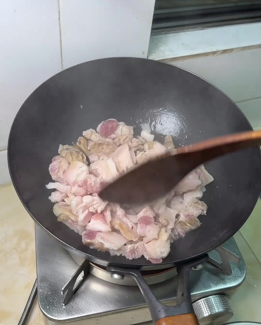 Tranches de poitrine de porc crue en train de frire dans une poêle chaude.